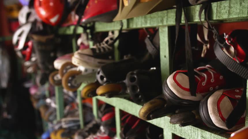 A green storage cubby filled with sneakers and roller skates