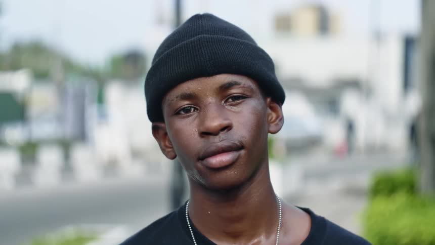 A teenage boy poses for a photo on a street corner