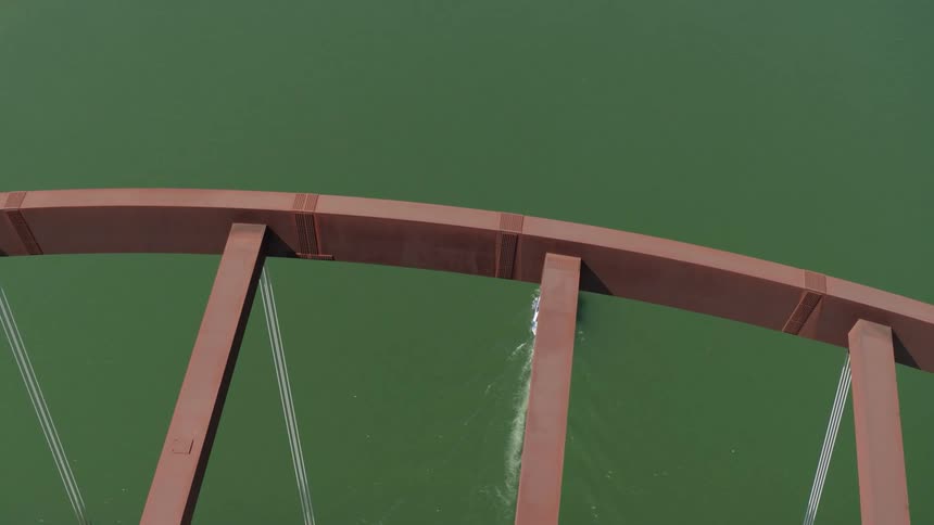 An aerial view of people on a boat as it drives past a bridge