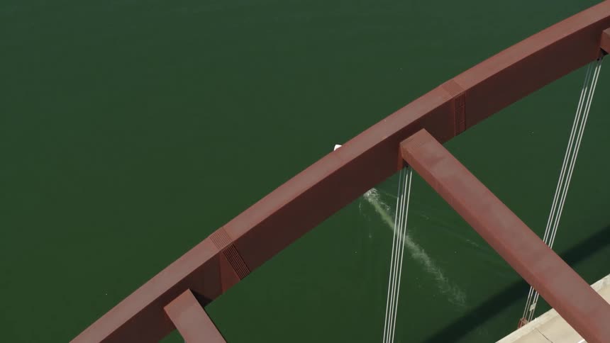 A boat travels a river under a bridge