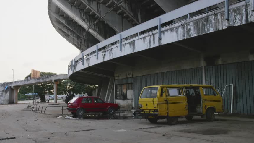 A city with an old stadium with vehicles with the sky and clouds in the background