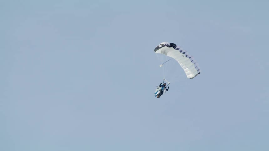 A paraglider glides through the air on a clear day