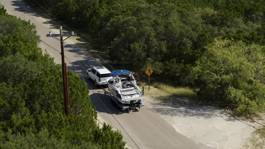 Car towing a boat on a rural road
