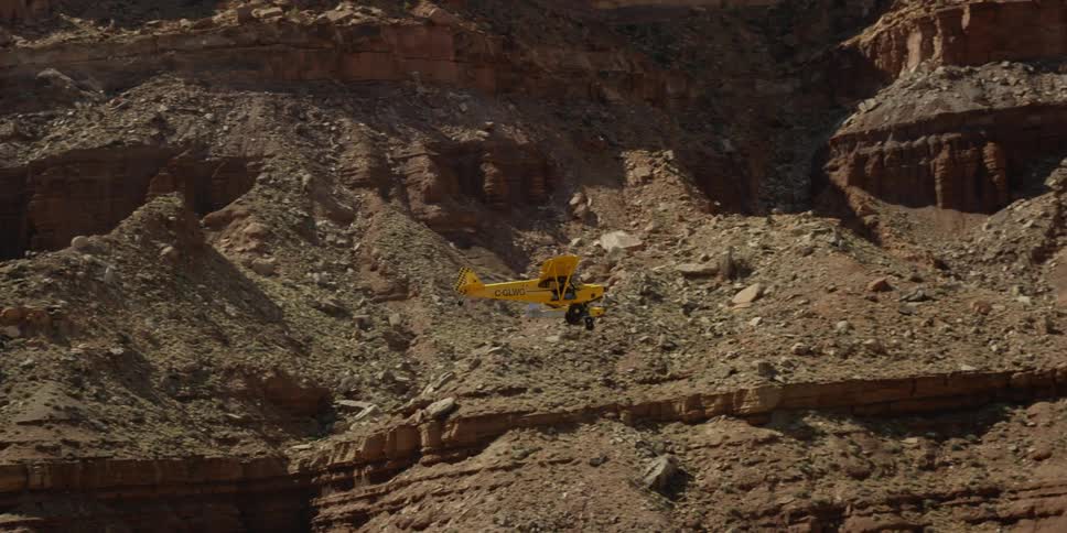 Two airplanes fly between mountains