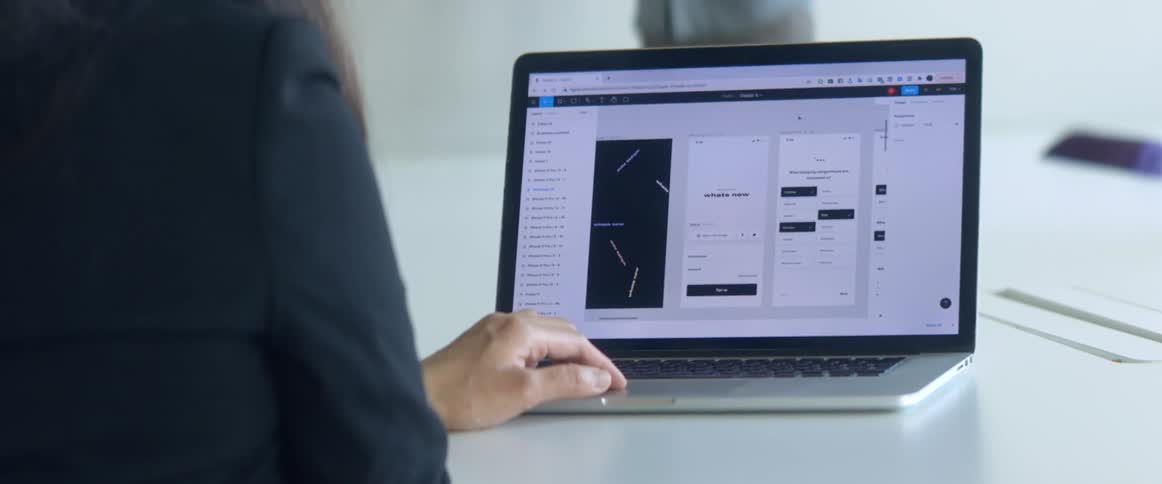 A woman sitting at a table uses the touch pad on her laptop computer to interact with her software