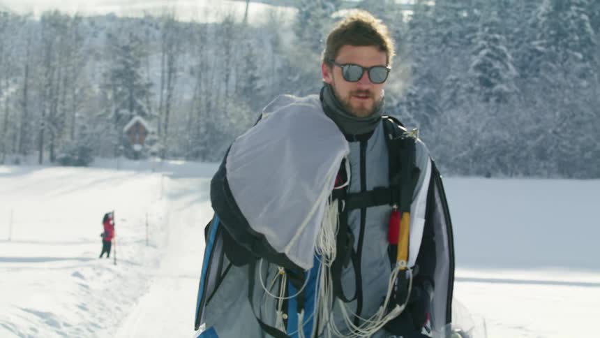 A man smiles as he walks up a snow slope