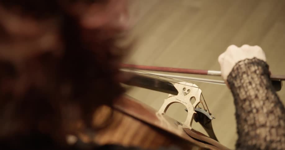 A woman uses a bow to play the cello