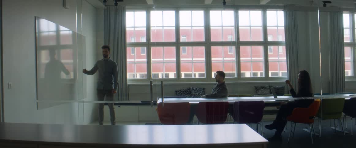 Office workers in a roomtalking with a worker at a board