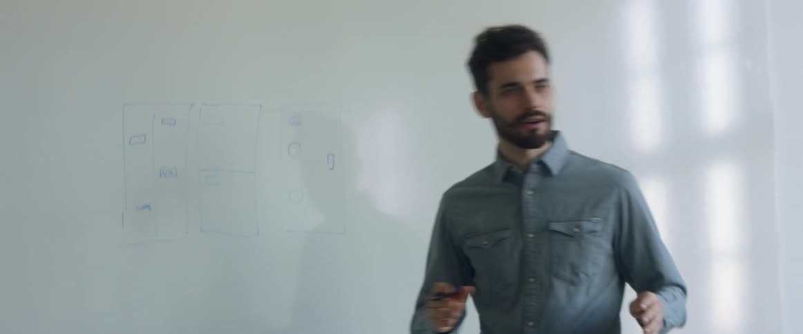 A man with a shirt and a market in a room with a whiteboard