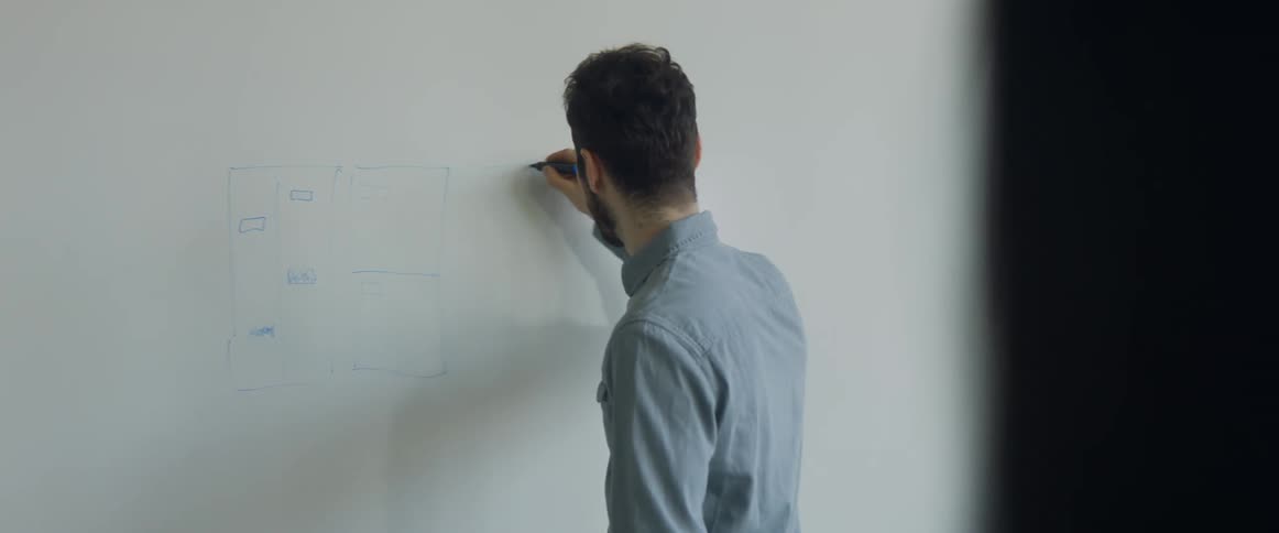 A man turns and diagrams on a white board