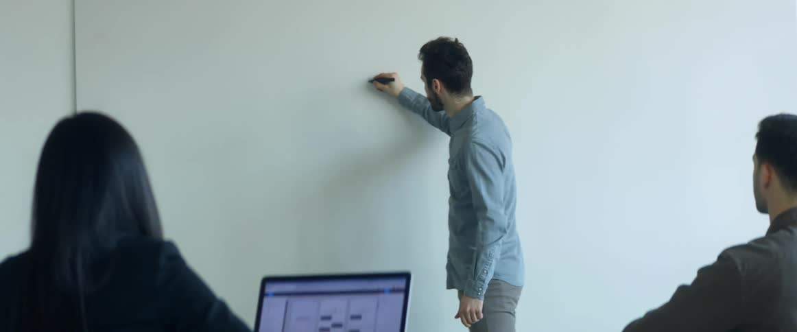 Man writting on a whiteboard in an office meeting in the conference room
