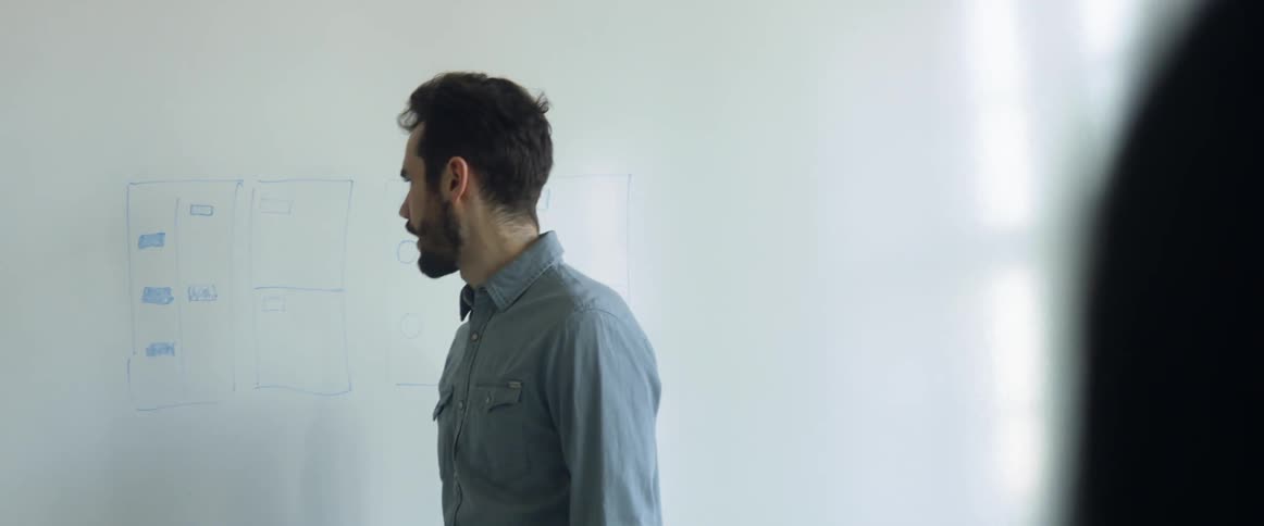 A man stands at a whiteboard while making a diagram during his lecture