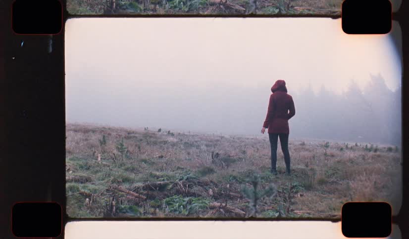 A woman standing outdoors in a field during the winter on analog Film 16mm