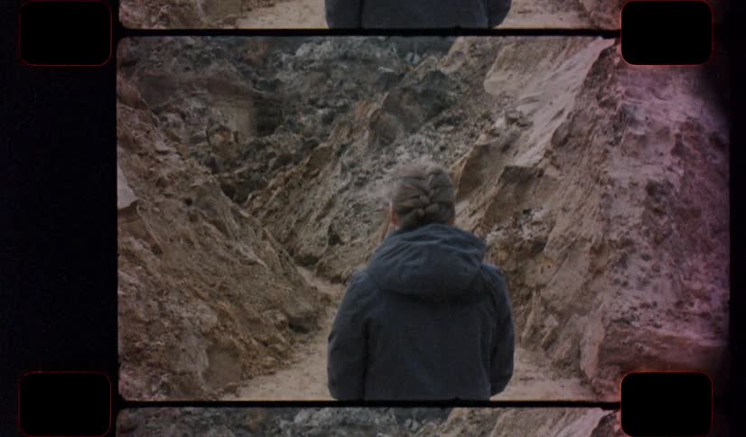 Film footage of a woman hiking at the base of a cliff on analog Film 16mm