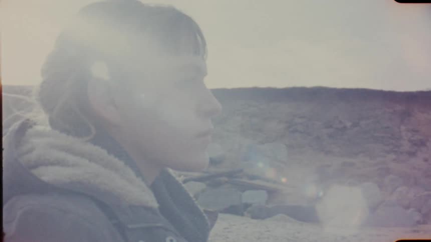 A woman stands at the base of a hill and looks in to the distance on analog Film