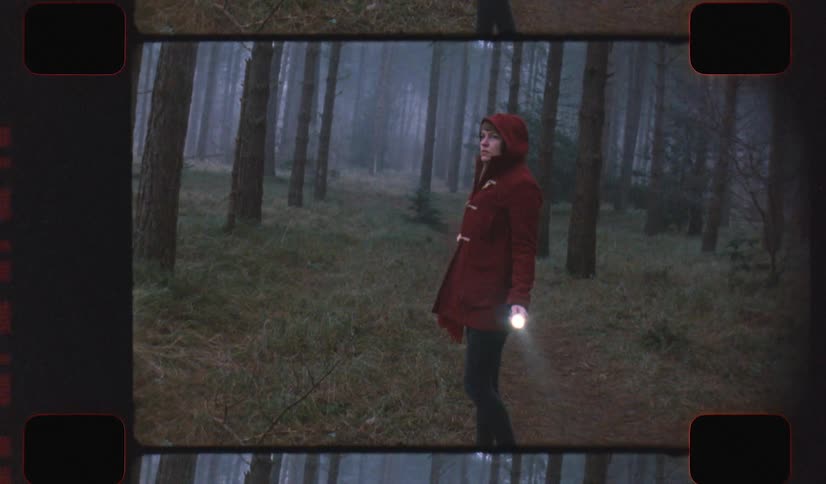 A woman in a forest with a flashlight with trees the sky and clouds in the background on analog Film