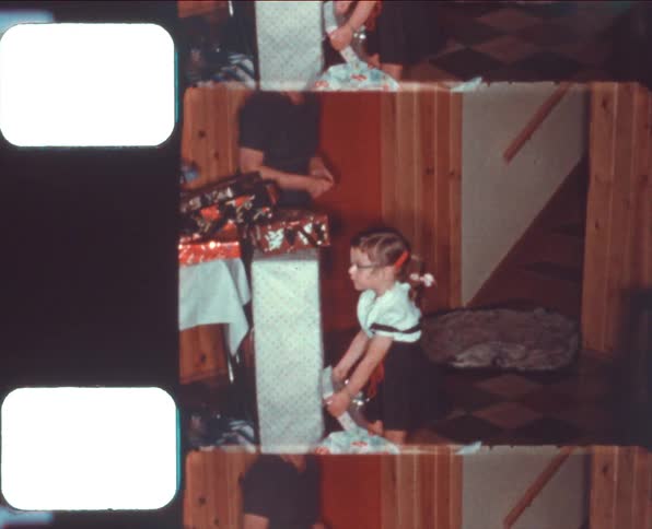 A woman and a girl in a room looking at christmas presents with a stairway in the background