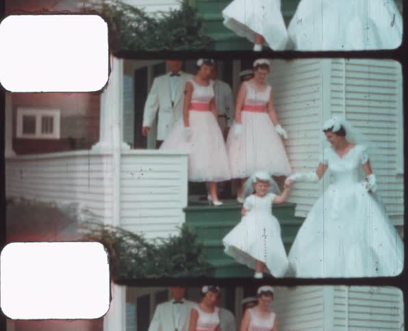A wedding party walking out of a house