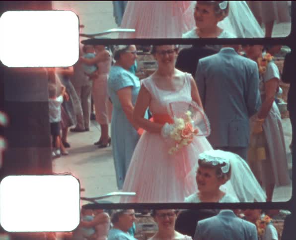 Flower girl and maid of honor walk through crowd of family and friends at wedding carrying bouquets