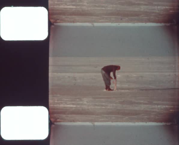 Man rolling wire on a pole in a plain caught on vintage film