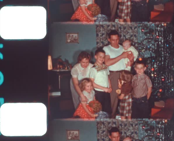 Family posing next to a christmas tree at home caught on vintage film