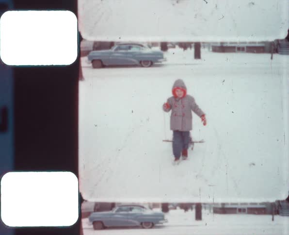 A boy laughs as he pulls a sled back toward his house