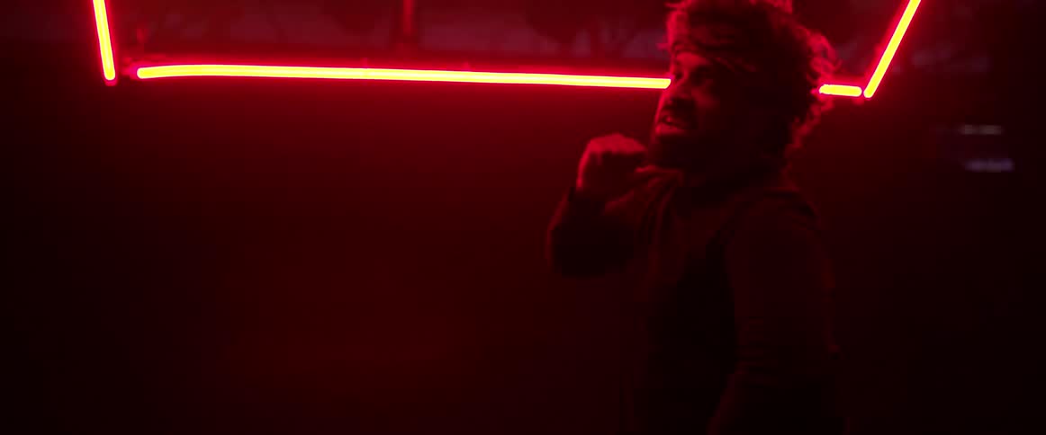 Man wearing a head band dancing on a dark room under red neon lights