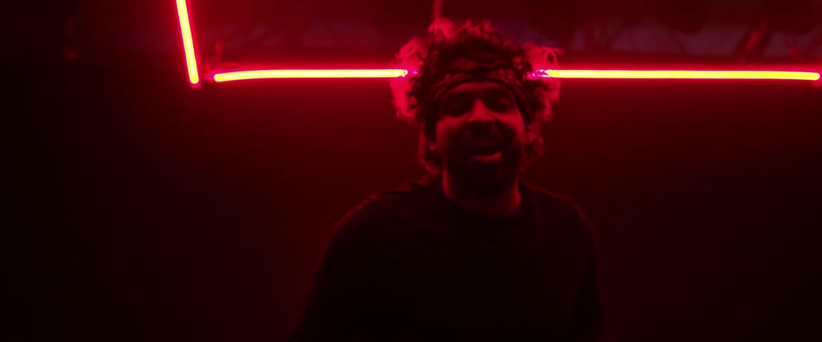 A man sings on under bright neon lights