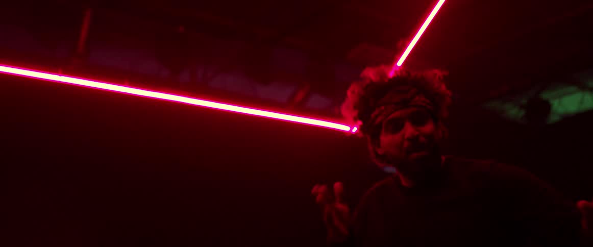 Man wearing a head band dancing on a dark room under red neon lights