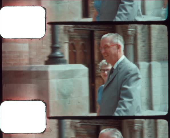 People arrive at building across from large house wearing their sunday best