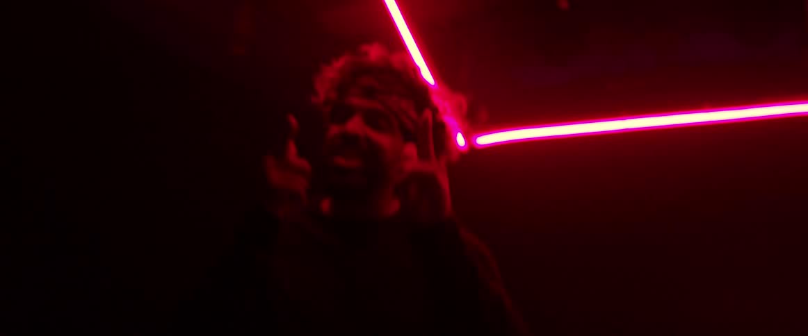 Man wearing a head band dancing on a dark room under red neon lights