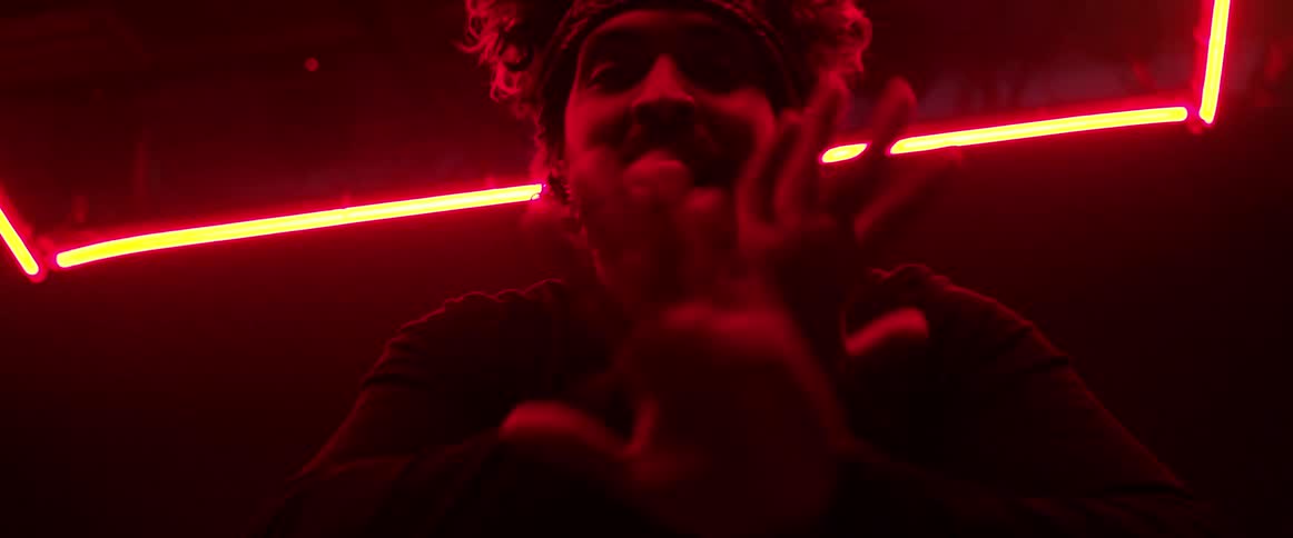 Man wearing a head band dancing on a dark room under red neon lights