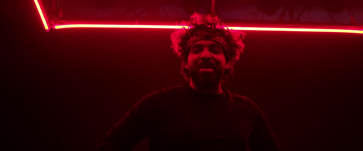 A man sings under bright neon lights