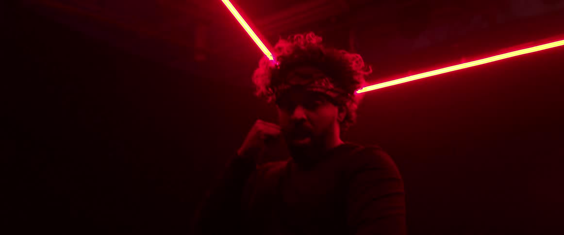 Man dances in dark room lit by red and yellow neon lights