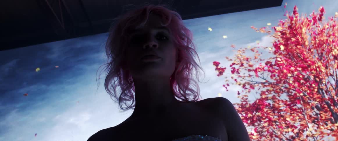 A woman standing and staring with a screen behind her