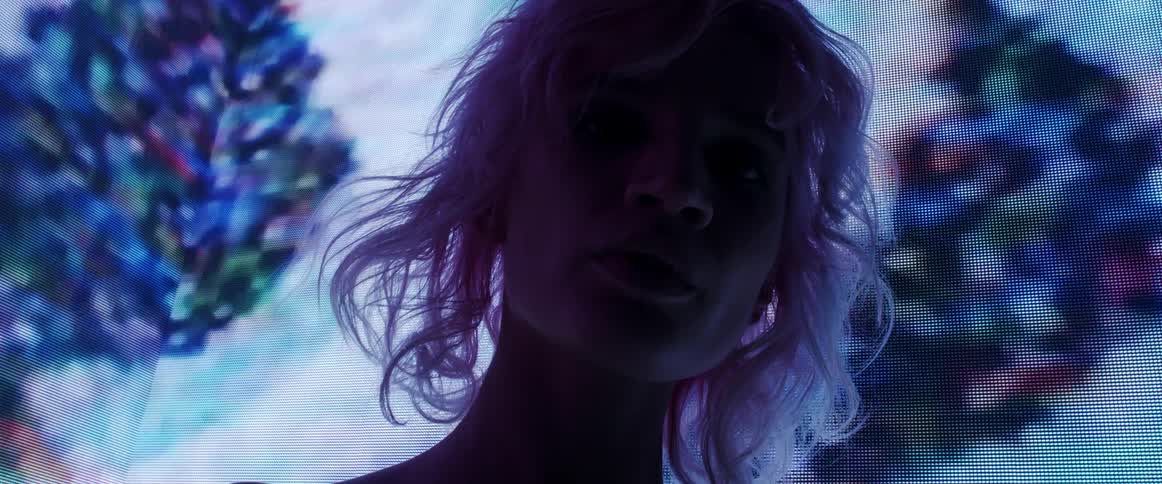 A model tilts her head as she poses in front of a digital screen