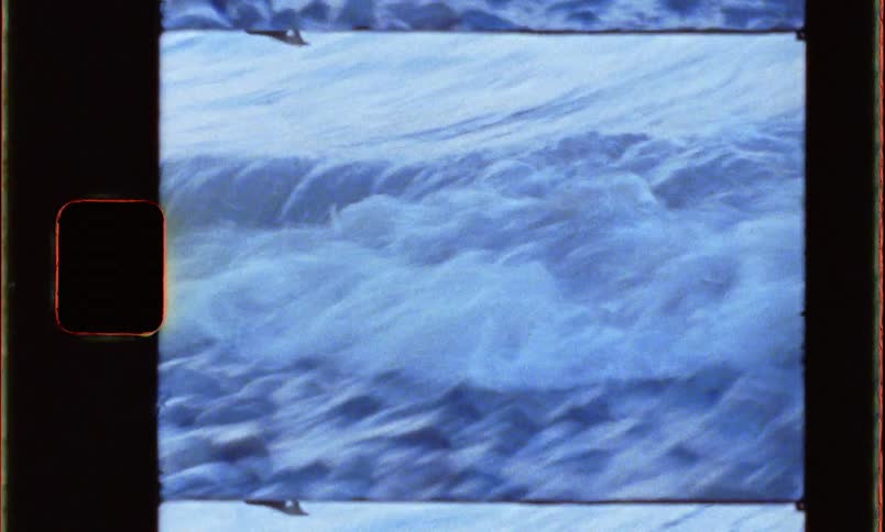 Small waves washing over the rocks on the shoreline caught on vintage film