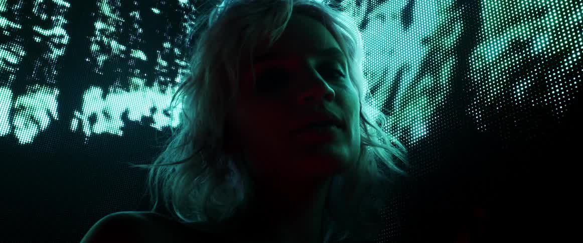 A woman standing and staring with a screen behind her
