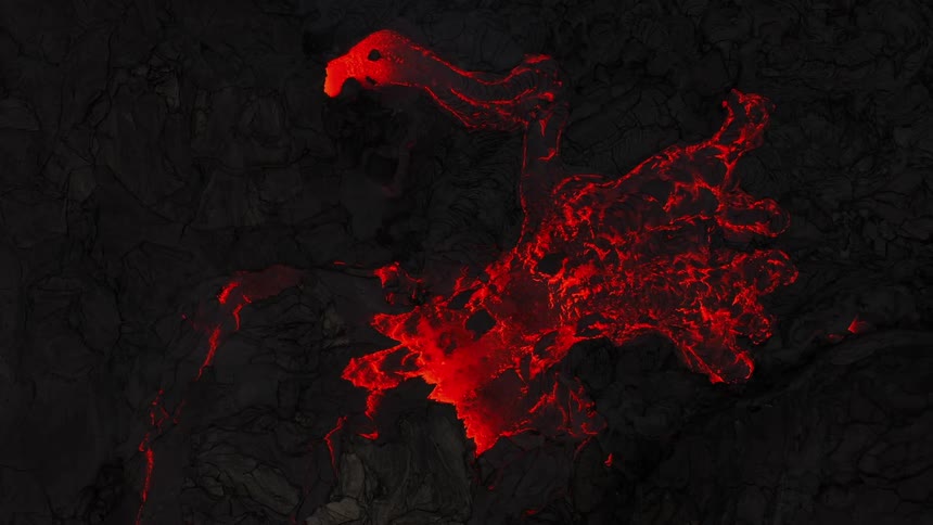 As a volcano erupts there is a large amount of glowing hot molten lava flowing out of it