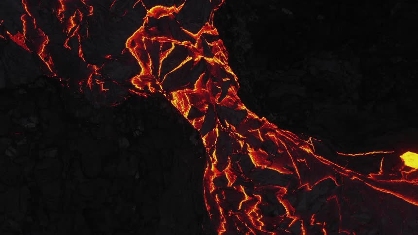 Hot molten lava moves slowly as it glows in the darkness