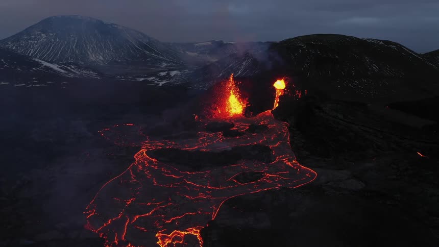 Volcano erupts as a river of molten hot lava glows in the darkness