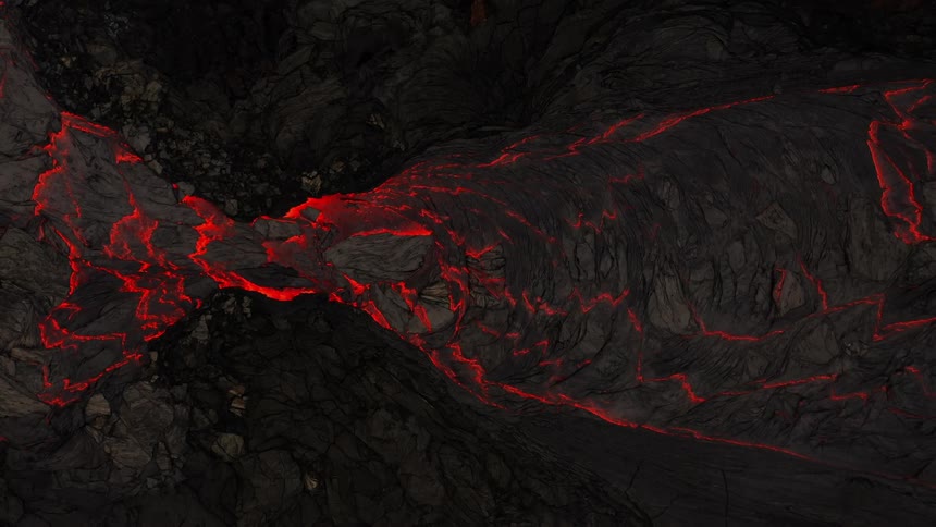 River of molten hot lava moves slowly as it glows in the darkness
