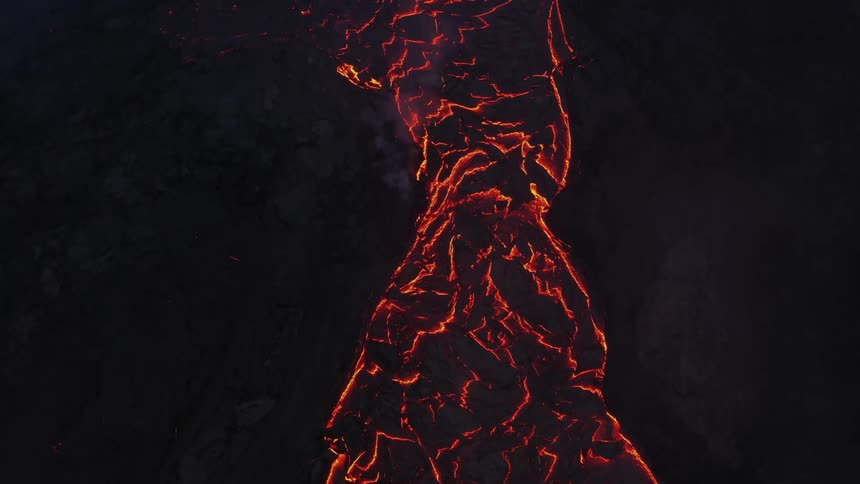 A fire on a mountain range glows and burns at night