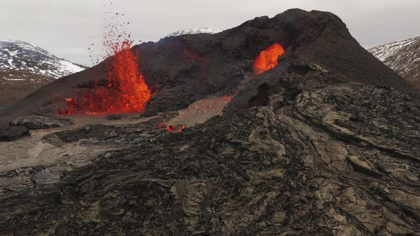 A volcano erupts and spews hot lava into the air