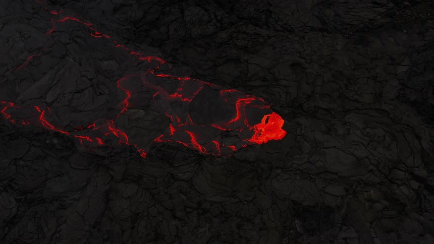 Aerial view of hot red lava erupting from a volcano at night