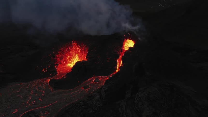 Aerial view of hot red lava erupting from a volcano at night