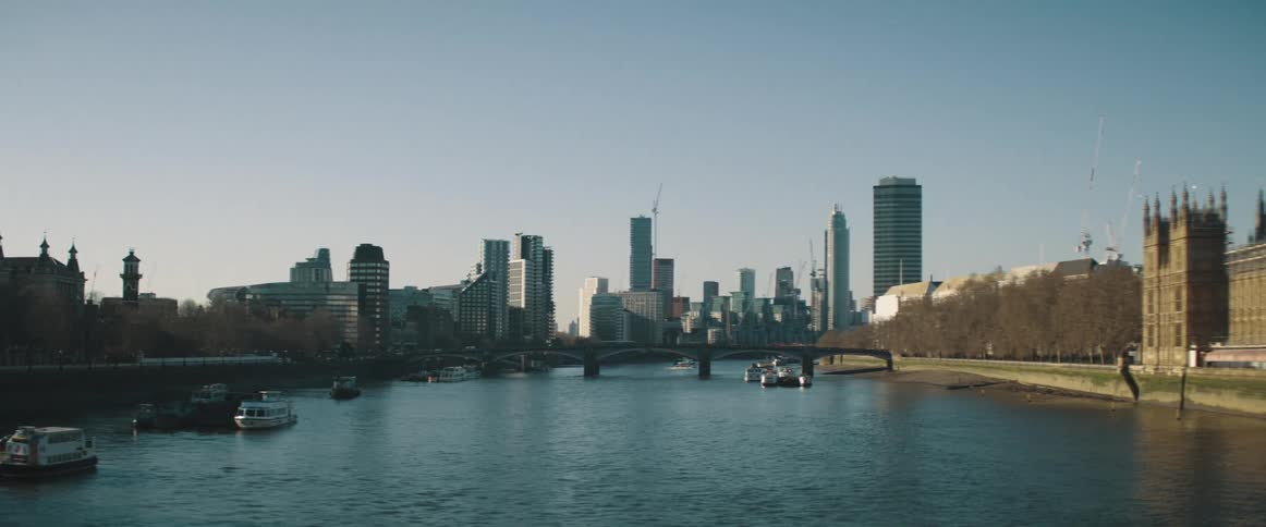 A city on the banks of a waterway that has a bridge and boats in the water