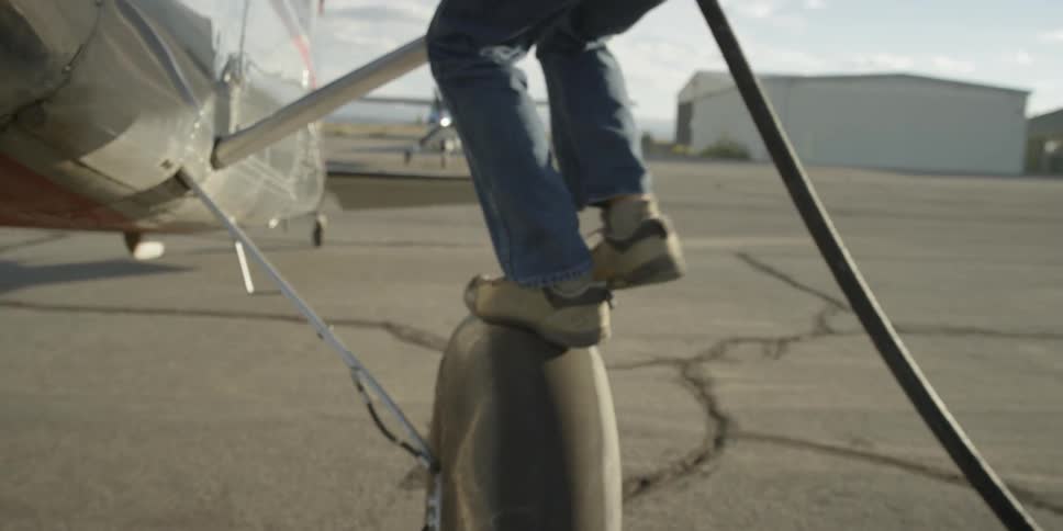 A man climbs on the wheel to fuel a plane