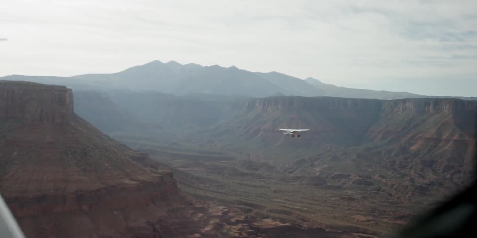 A plane flies high over a canyon