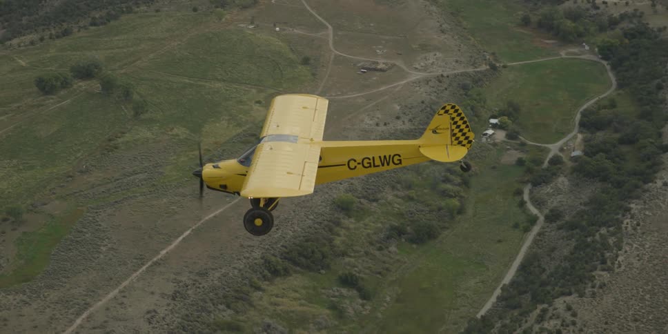A yellow plane flies high in the air